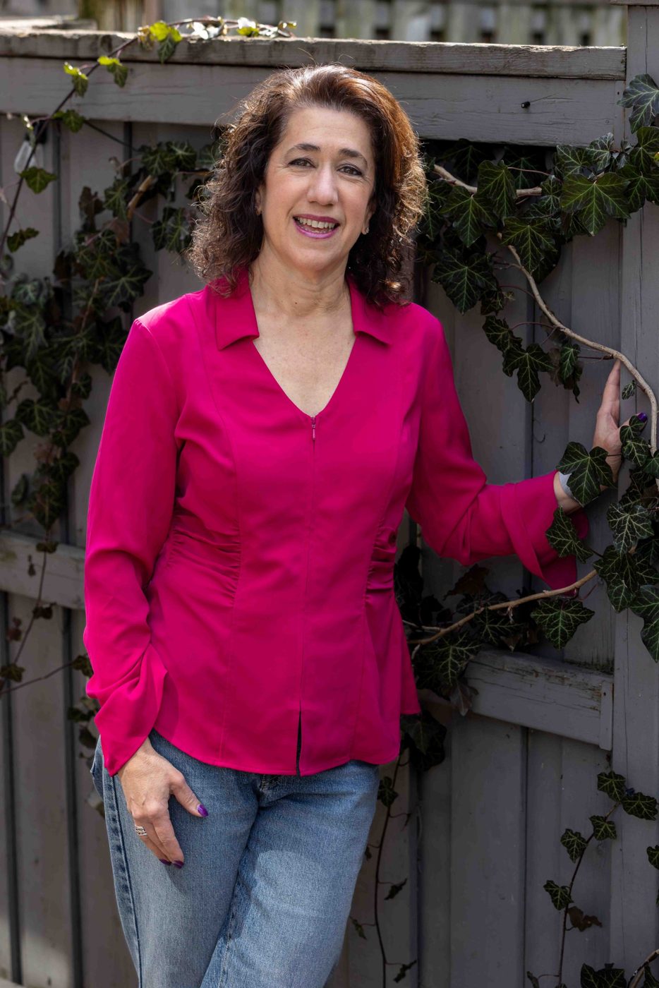 Sara Curwen standing beside an ivy-covered fence